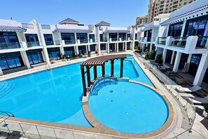Un hôtel à plusieurs étages doté d’une piscine centrale, d’un espace extérieur aménagé et de balcons.