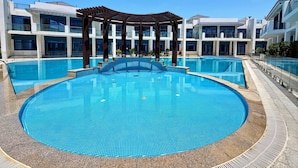 En stor udendørs swimmingpool omgivet af moderne bygninger med altaner.