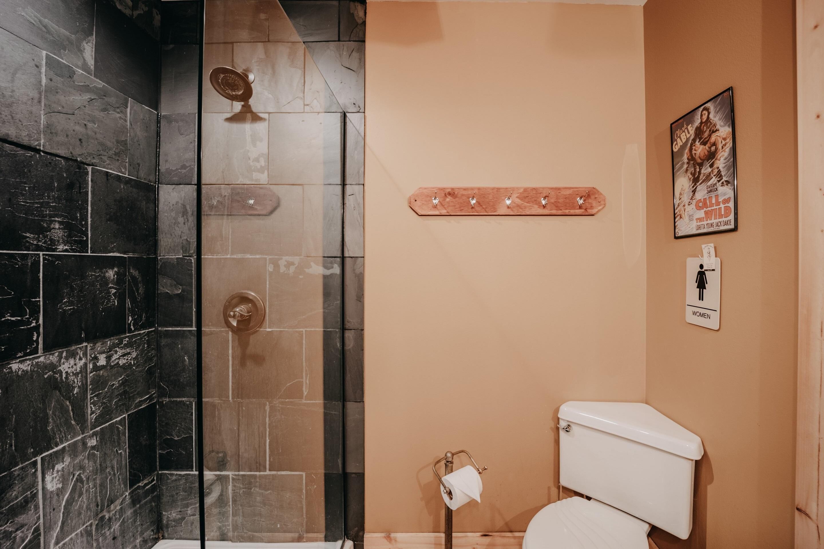 A bathroom with a shower, toilet, and a towel rack.