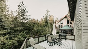 Una terraza de madera con mobiliario exterior, una parrilla y una zona de estar cubierta.