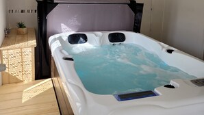Ein modernes Badezimmer mit einer großen Badewanne, Holzboden und einer kleinen Pflanze auf der Ablagefläche.