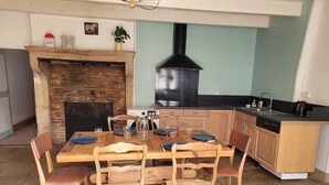 Ein Essbereich mit Kamin aus Ziegelsteinen, einem Holztisch und Stühlen.