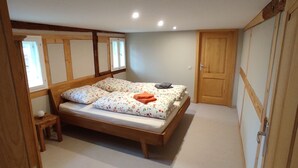 A bedroom with a wooden bed, a nightstand, a window, and a door.