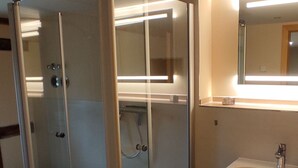 A bathroom with a glass-enclosed shower, a white sink, and a mirror above the sink.