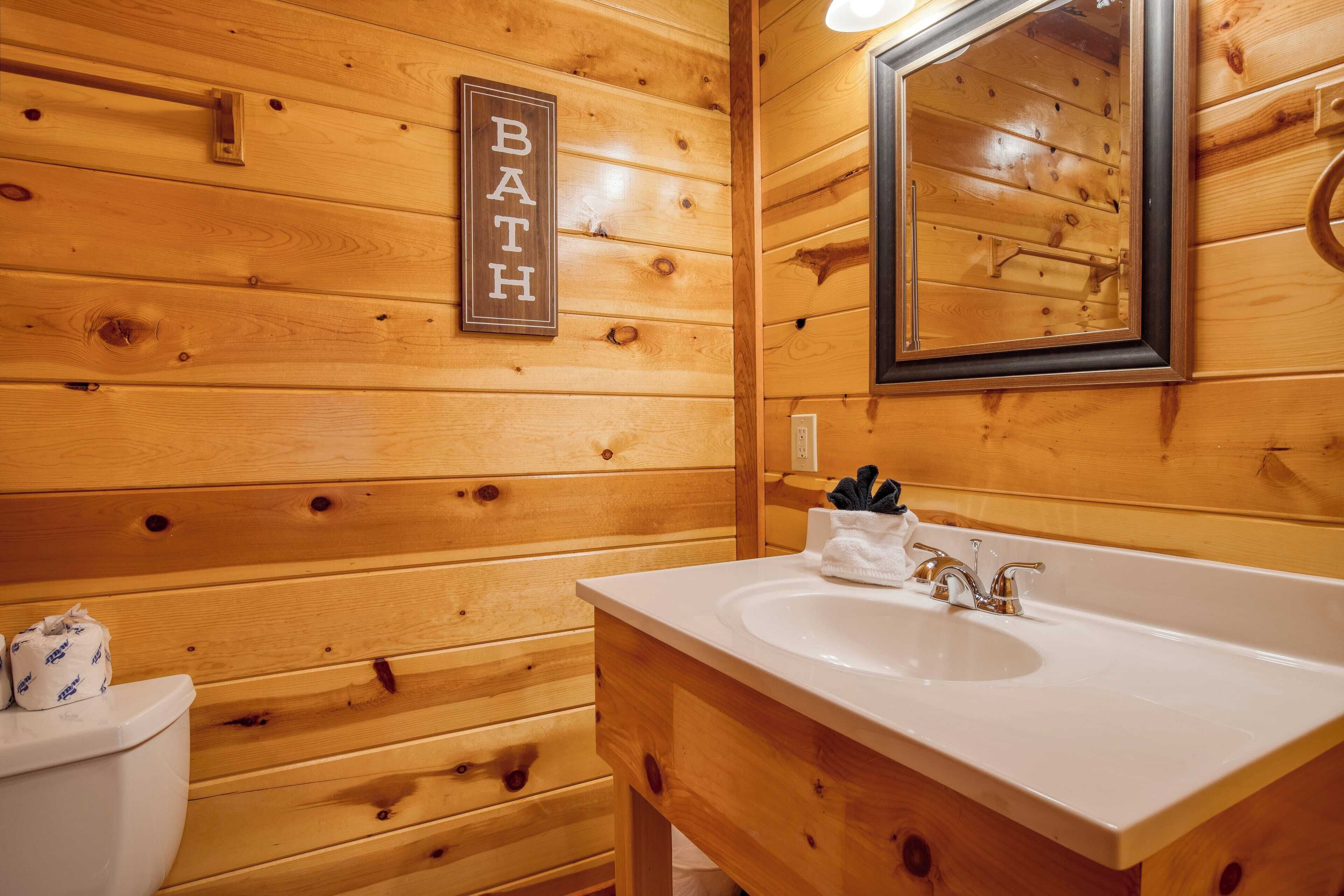 Un baño de madera con lavamanos blanco, espejo y un letrero que dice "BATH".