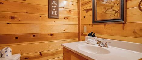 Un baño de madera con lavamanos blanco, espejo y un letrero que dice "BATH".