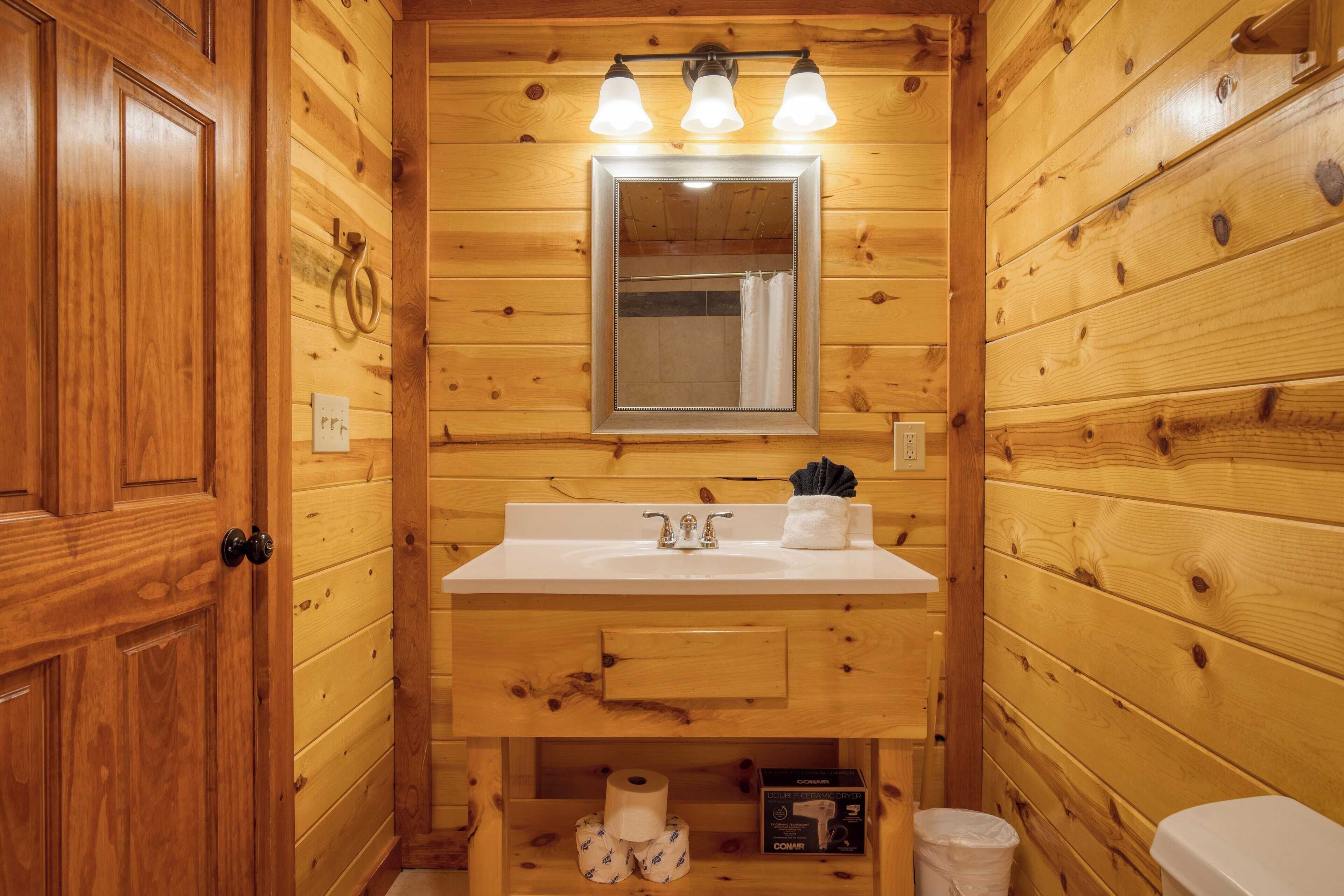 A wooden cabin bathroom with a sink, mirror, and toilet.