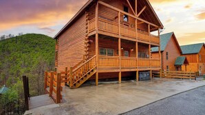A large wooden lodge with a balcony and a staircase leading to the entrance.