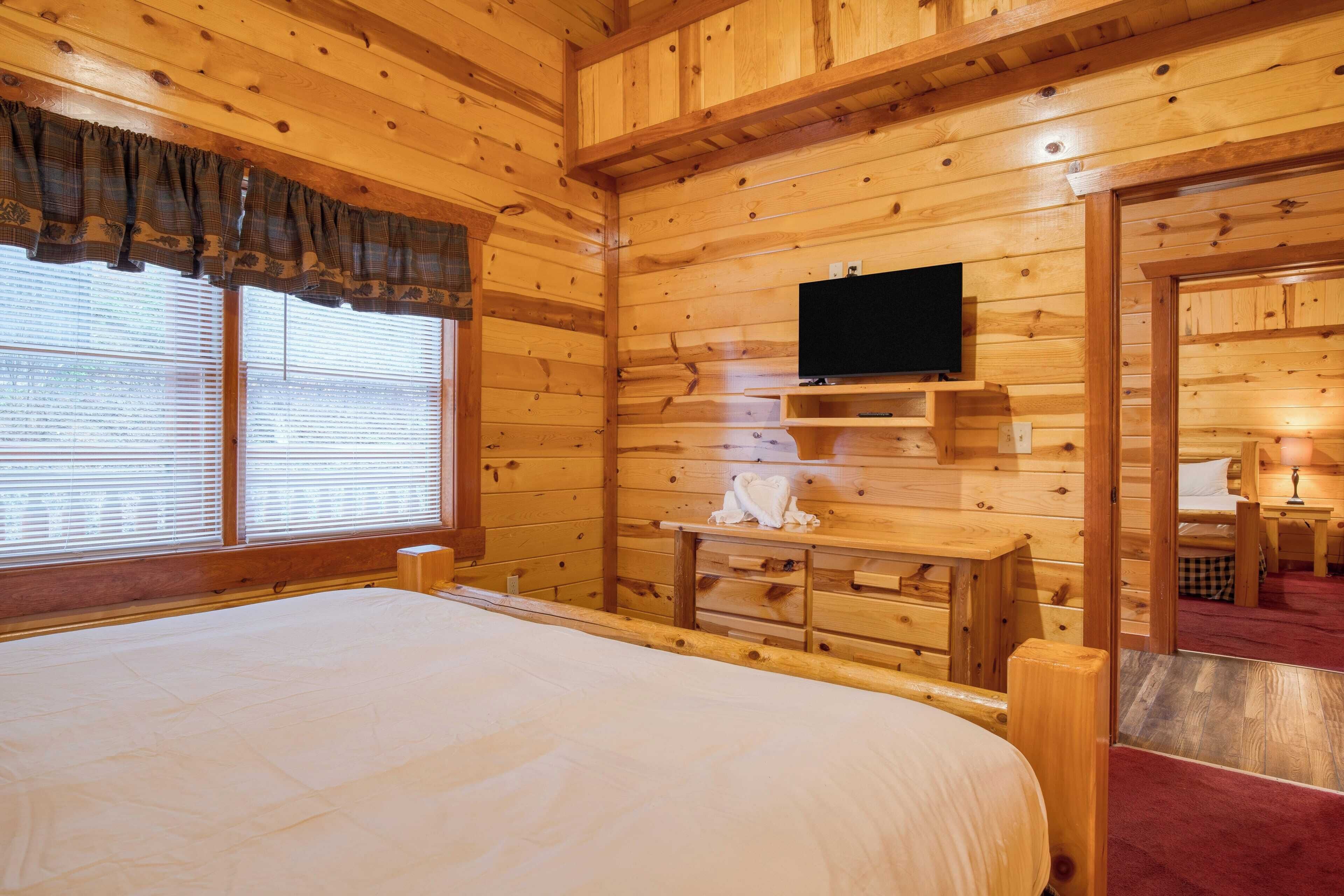 Een kamer met houten lambrisering, een bed, een flatscreen televisie, een bureau en een spiegel.