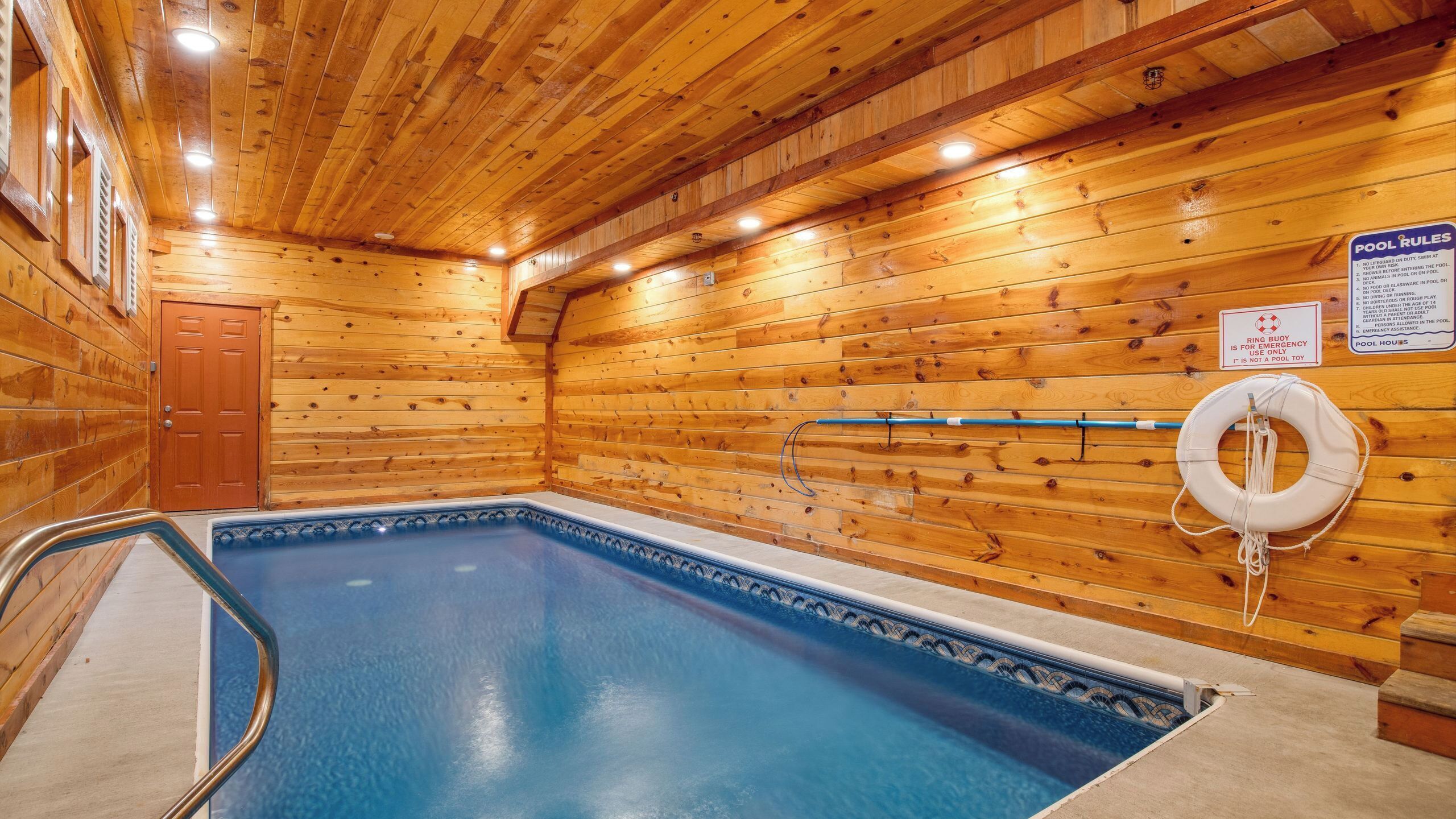 An indoor pool with wooden walls and a lifebuoy on the wall.