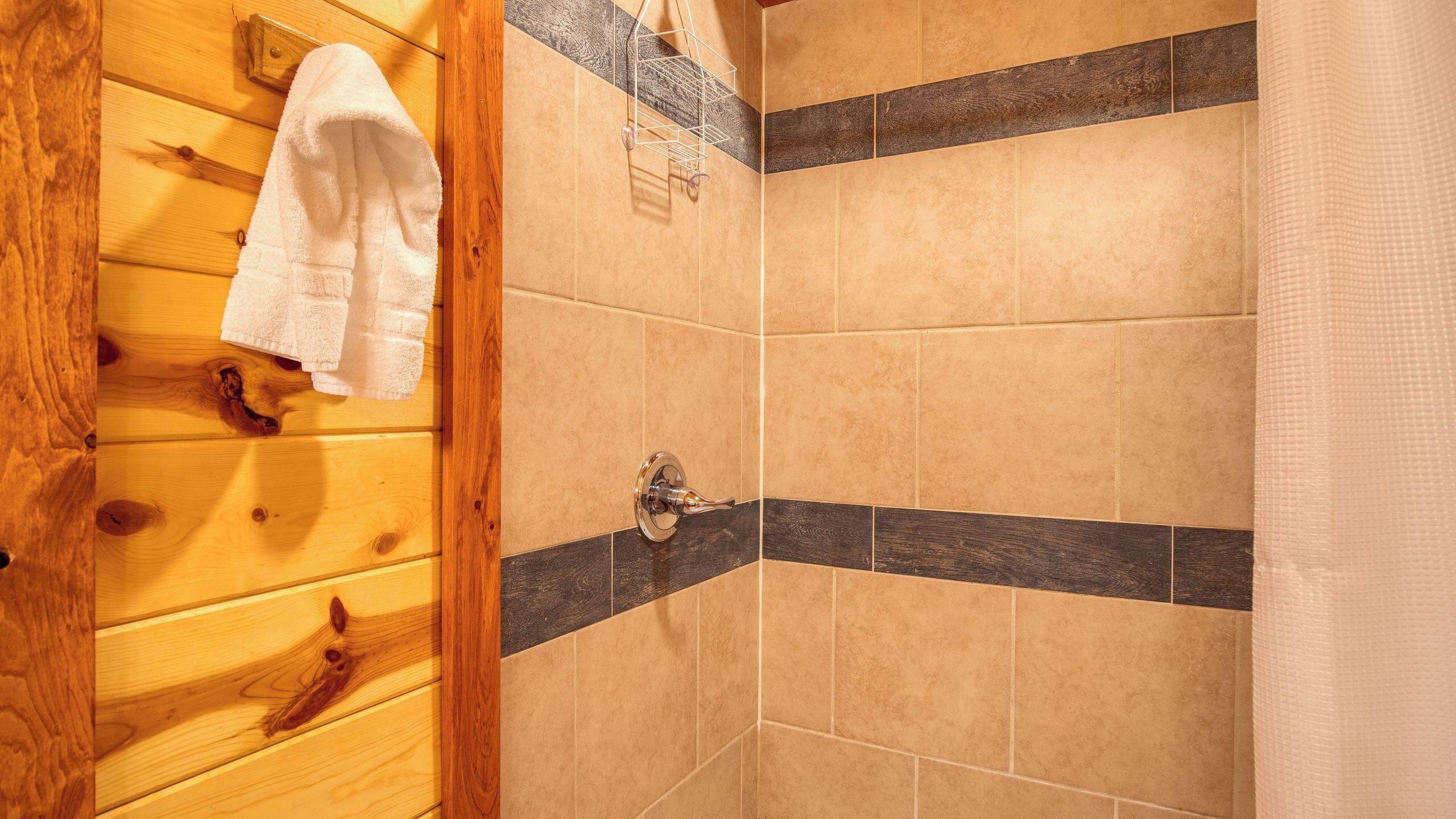 A shower area with wooden walls, a towel rack, and a shower control.