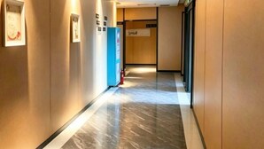 Un pasillo con piso de mármol, paredes de madera y cuadros enmarcados.