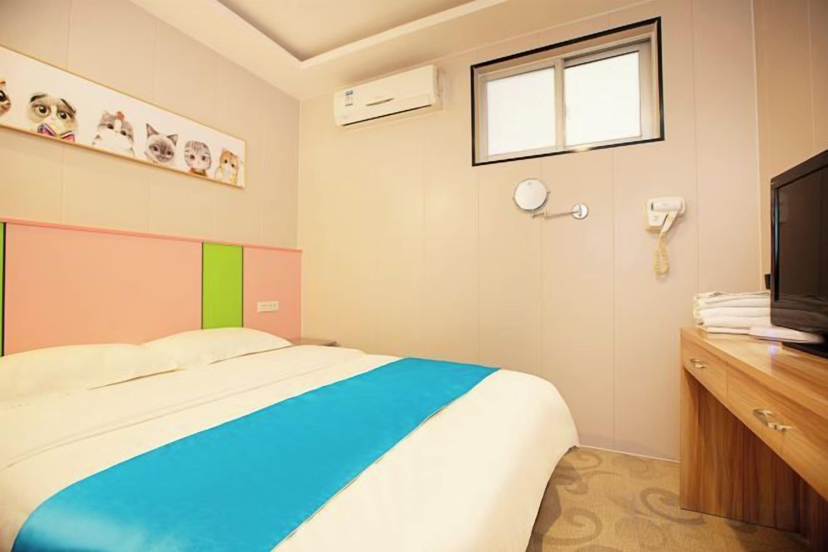 A hotel room with a bed, a desk, a television, and a window.