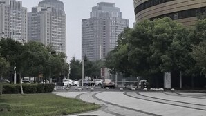Una carretera sinuosa con automóviles, rodeada de árboles y edificios altos.