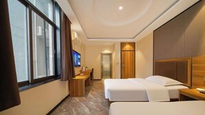 Una habitación de hotel con dos camas, un escritorio, un televisor y una puerta que da a un baño.
