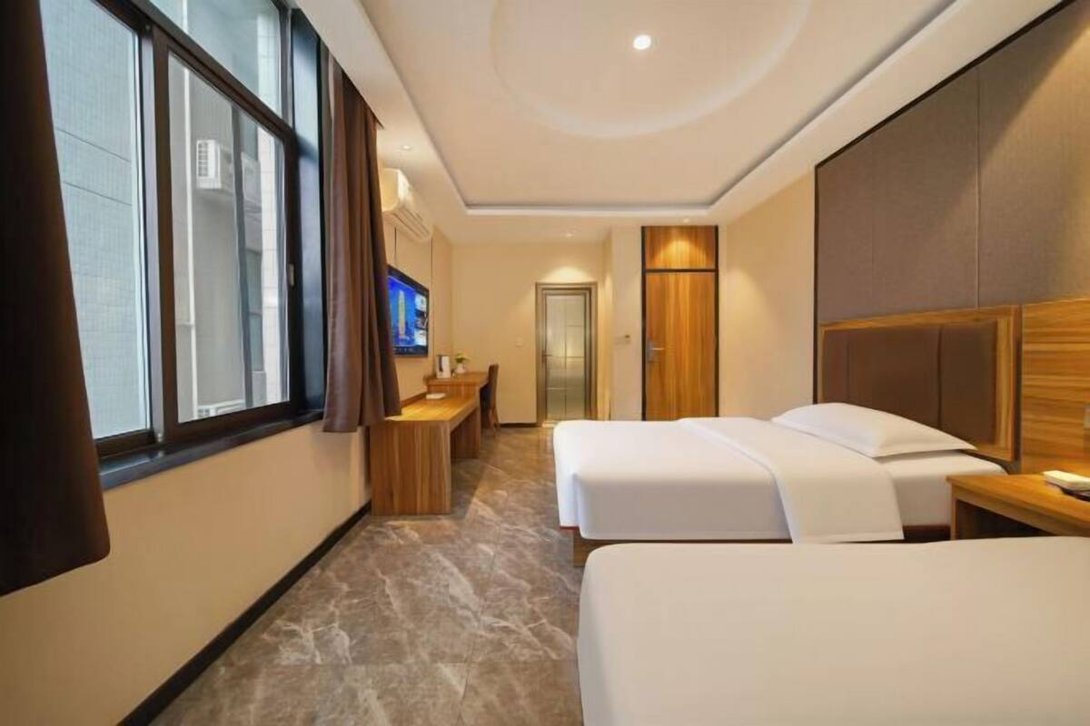 Una habitación de hotel con dos camas, un escritorio, un televisor y una puerta que da a un baño.