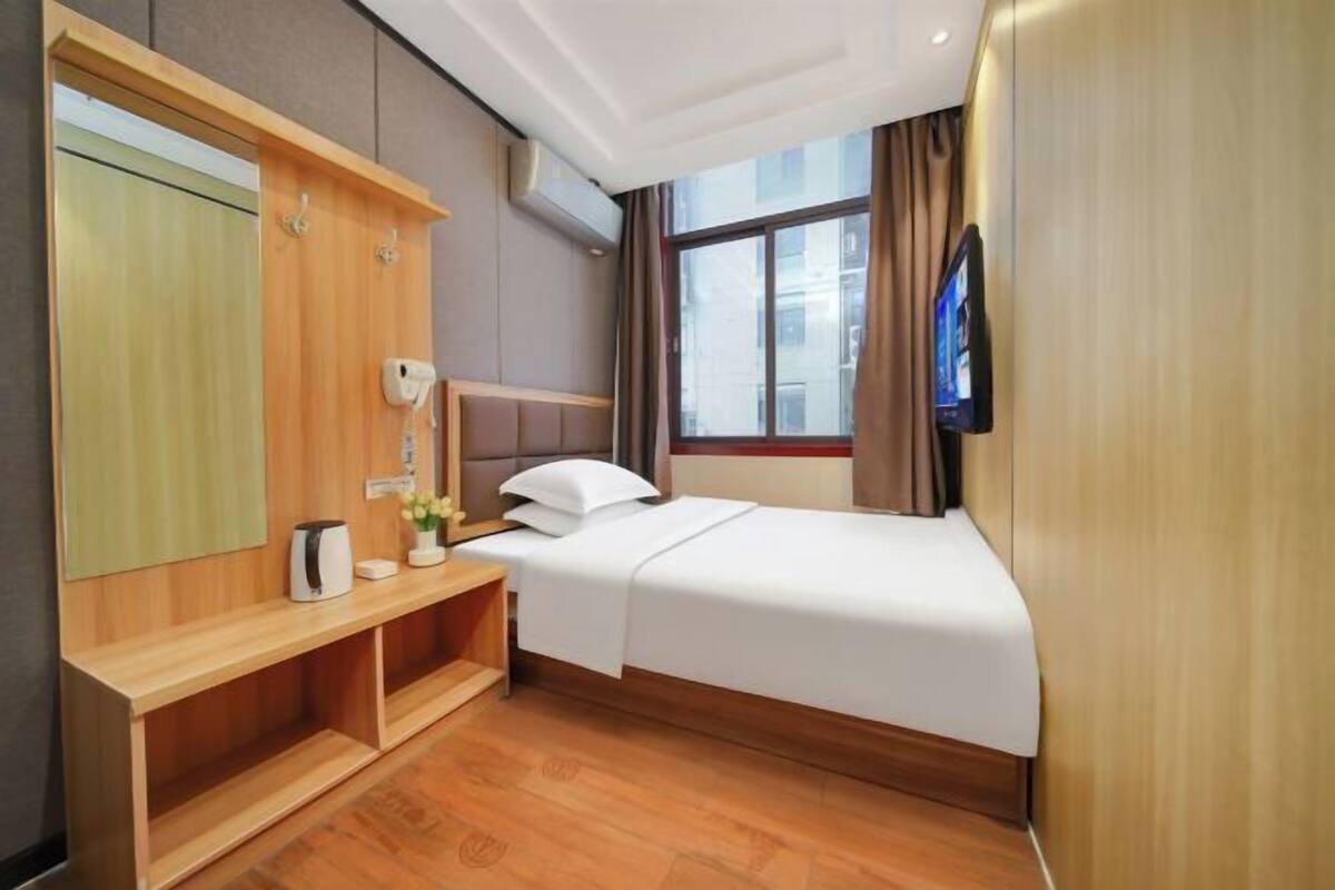 Habitación de hotel con cama, televisión, espejo, escritorio de madera y ventana.