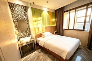 Ein Hotelzimmer mit einem Bett, einem Nachttisch, einem Spiegel und einem Fenster.