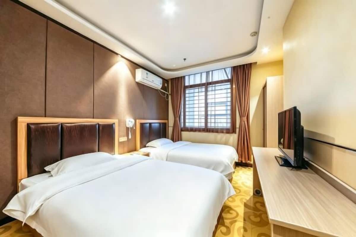 Habitación de hotel con dos camas, televisión y ventana con cortinas.