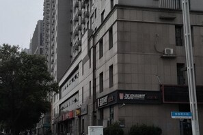 A multi-story building with commercial signage, a street sign, and a clear sky. - Jiayuan Business Hotel (Zhengzhou CBD Exhibition Center) (Zhengzhou)