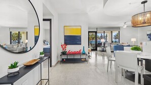 A modern living room with a large mirror, a console table with decorative items, a sofa, and a coffee table.