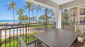 A balcony with a view of the beach and palm trees.