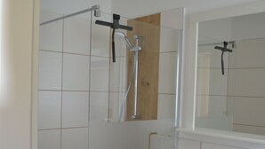Ein Badezimmer mit Dusche, Waschbecken und Spiegel.