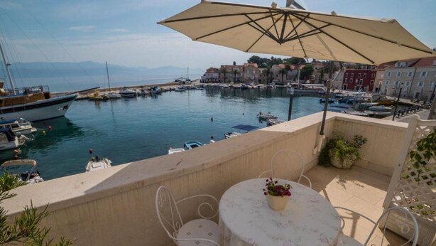 Una terraza con mesa y sillas, con vistas a un puerto deportivo con barcos y edificios.