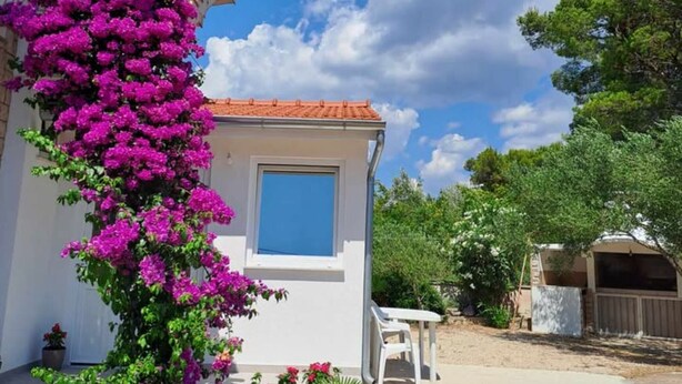 A white building with a red-tiled roof, a small window, and a white chair outside. - Apartments Dana - Two Bedroom Apartment 1 (Srima)