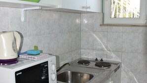 A compact kitchen with a microwave, a kettle, and a sink.