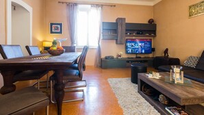 A living room with a dining area, a TV, and a sofa. - Charming Apartment in Zadar with City Views - Three Bedroom Apartment (Zadar)