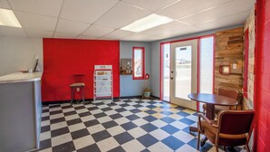 Un restaurant avec un sol à carreaux, des murs rouges et bleus, un comptoir avec des tabourets et une porte donnant sur l’extérieur.