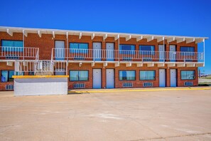 A multi-story motel with a brick facade, balconies, and a parking lot.