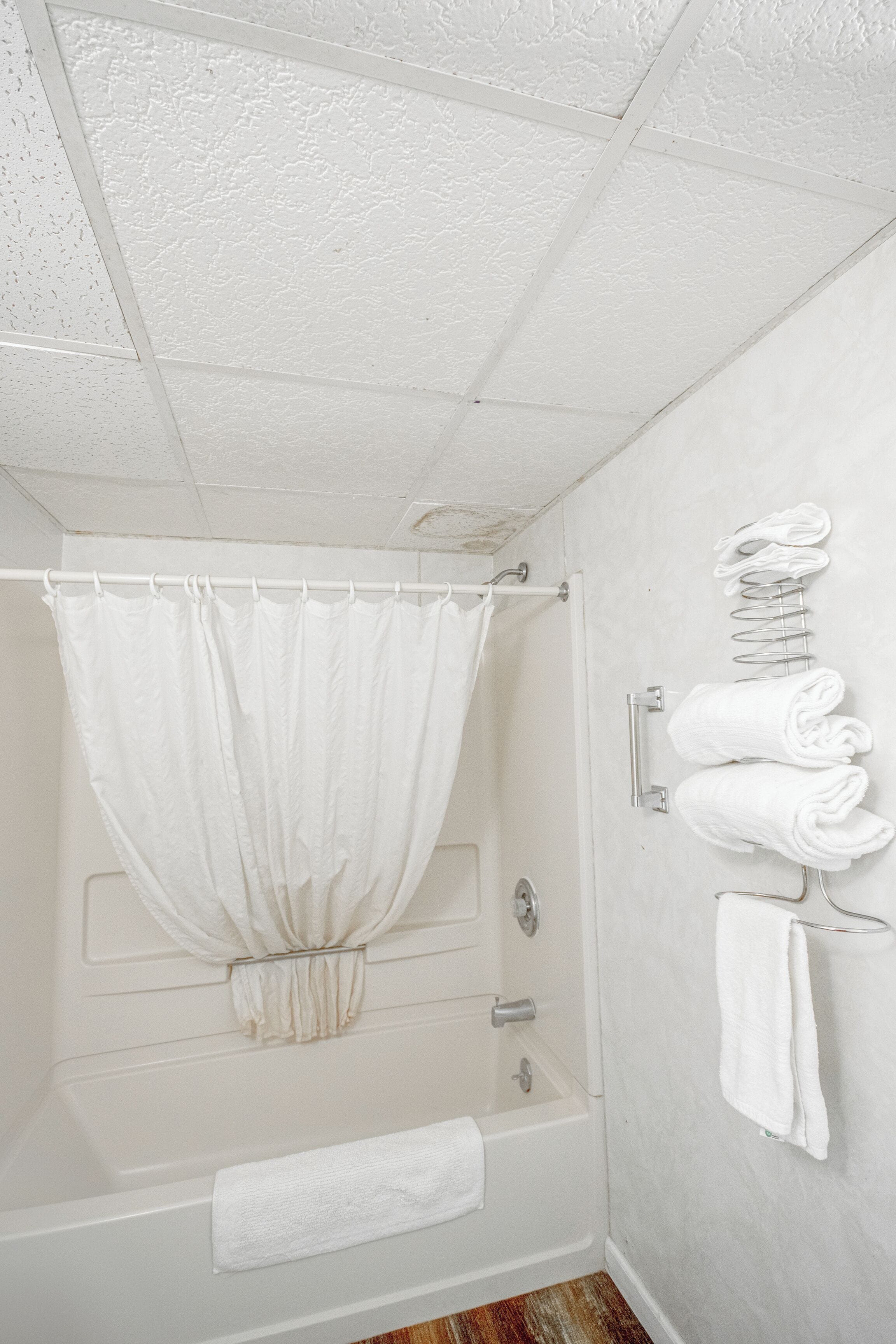 A bathroom with a bathtub, a shower curtain, and a towel rack with towels.