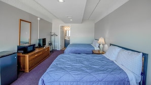 Une chambre avec deux lits, une commode, un téléviseur et un miroir.