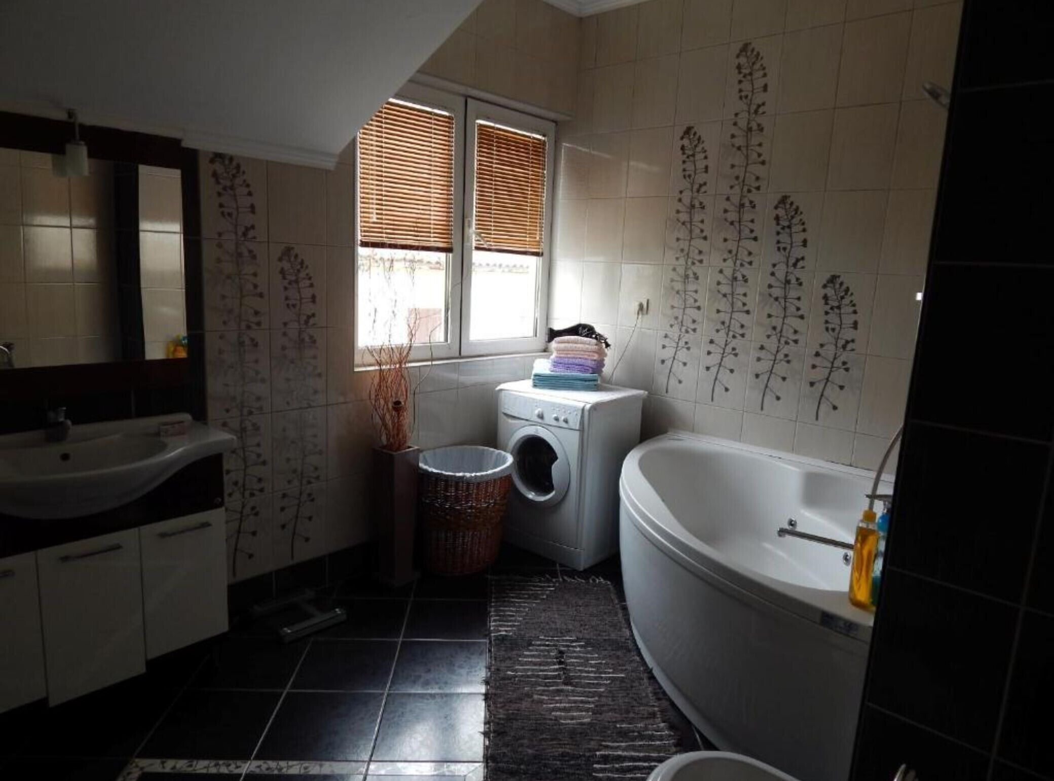 A compact bathroom with a sink, a washing machine, and a bathtub.