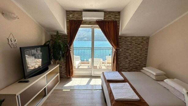 A bedroom with a balcony, a television, and a bed with towels.