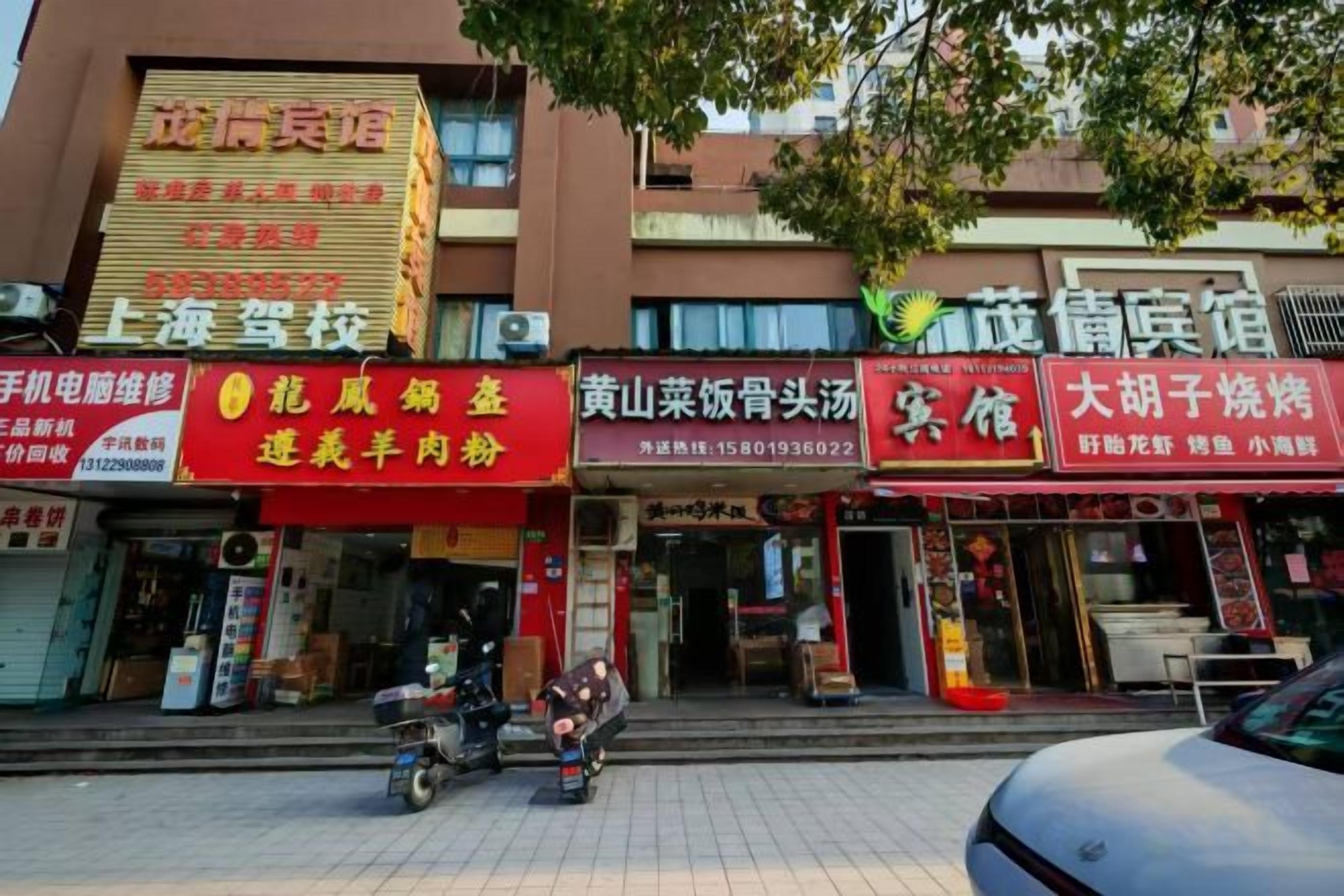 Una calle con varios comercios, incluyendo un restaurante con un letrero rojo y una tienda con un letrero amarillo.