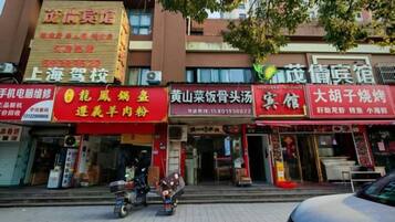 A street with multiple storefronts, including a restaurant with a red sign and a shop with a yellow sign.