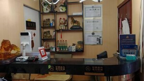 A reception desk with a counter, a coffee machine, and a display of various items including a teddy bear and a cat figurine. - Shanghai Maoyi Hotel (Shanghai)
