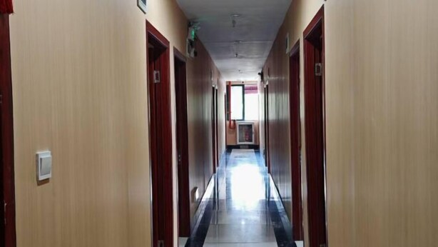 A long, narrow hallway with wooden doors on both sides and a tiled floor. - Shanghai Maoyi Hotel (Shanghai)