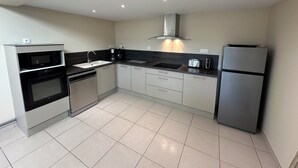 A modern kitchen with a built-in oven, microwave, and dishwasher, a stainless steel refrigerator, and a black countertop.