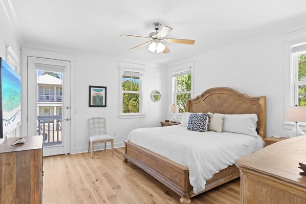 A bedroom with a wooden bed, white walls, a ceiling fan, and a balcony visible through an open door. - Near Inlet Beach Access&lake Powell, Pool, Patio Lounge G'day 30A by Avantstay (Panama City Beach)