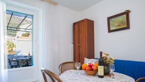 A dining area with a table set for two, a wooden cabinet, and a framed picture on the wall. - Comfortable Stay with Sea View in Petrovac - One Bedroom Apartment 3 (Petrovac na Moru)