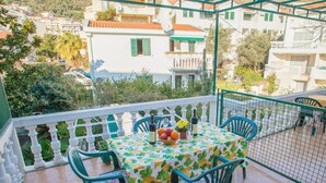 A balcony with a table set for two, chairs, and a bowl of fruit. - Comfortable Stay with Sea View in Petrovac - One Bedroom Apartment 3 (Petrovac na Moru)