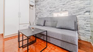 A modern living room with a grey sofa, a small table, and a white wardrobe. - Urban Nest Apartment - Apartment (Zagreb)