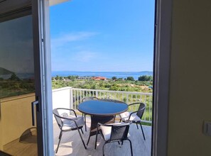 Ein Balkon mit Tisch und Stühlen, der Blick auf eine Küstenlandschaft bietet.