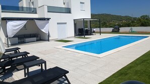 A modern villa with a swimming pool, outdoor seating, and a view of the hills. - Holiday Home Iva - Three Bedroom Holiday Home (Šibenik)