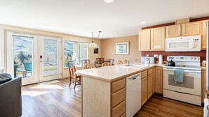 A modern kitchen with wooden cabinets, a central island, a built-in dishwasher, and a stove. - Mountain View Retreat - Condo in Chelan (Chelan)