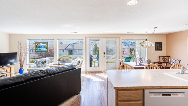 A modern living room with a sofa, a television, and a dining area with chairs and a table. - Mountain View Retreat - Condo in Chelan (Chelan)